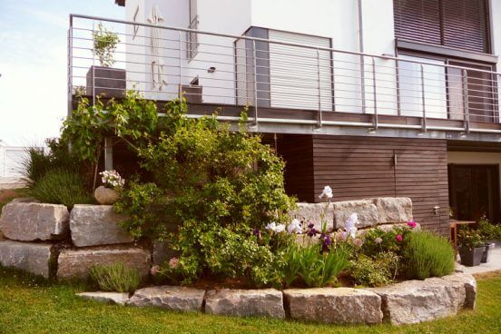 Ausschnitt eines Familiengartens mit moderner Gartengestaltung. Natursteinmauer mit Beet.